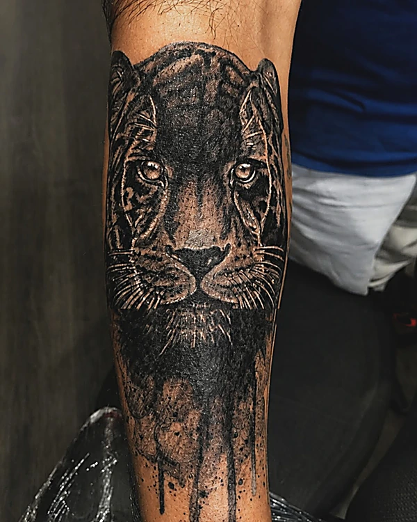 Pantera en realismo negro y gris con efecto de goteo, tatuada en el antebrazo